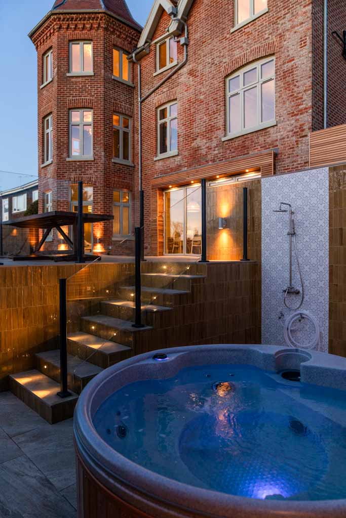 Modern bathroom with a walk-in shower, wall-mounted sink, and large mirror. The room is finished with light tiles and chrome fittings, giving a fresh and clean impression.