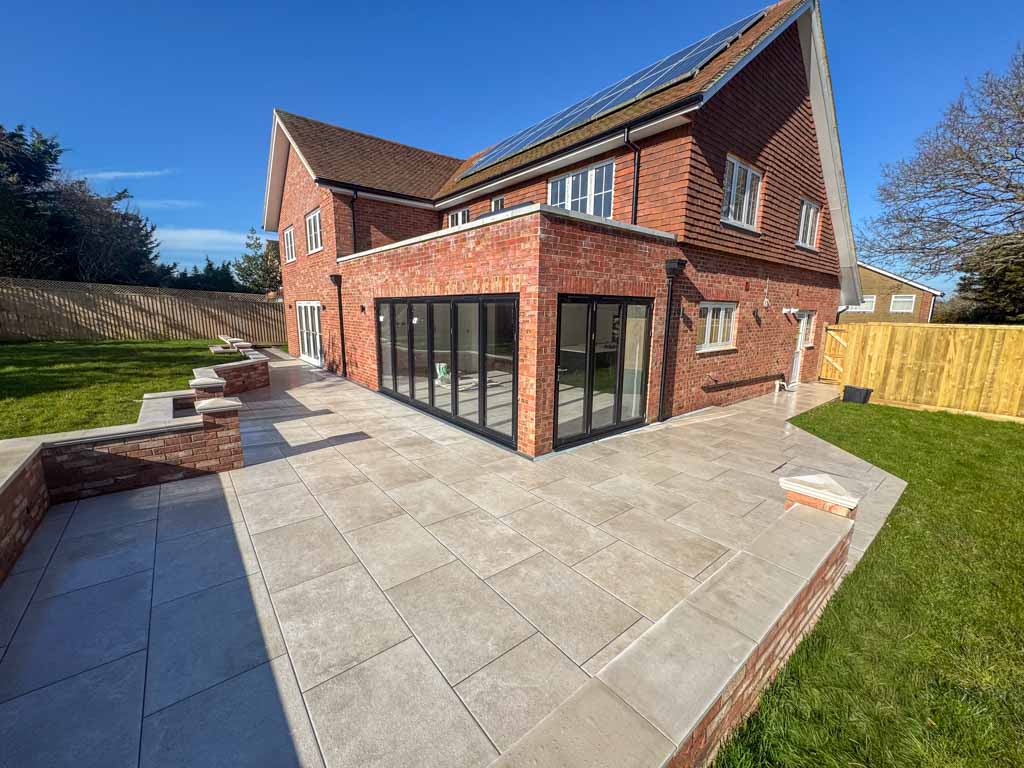 Spacious living room with a large sofa, coffee table, and a fireplace. Floor-to-ceiling windows provide views of the garden, and the room is decorated with soft colors, creating a cozy and welcoming atmosphere.