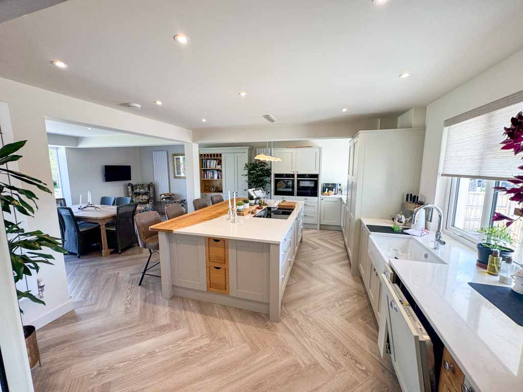 Dining area with a wooden table and chairs, adjacent to large glass doors that open to the garden. The room is filled with daylight and has a warm, inviting feel.
